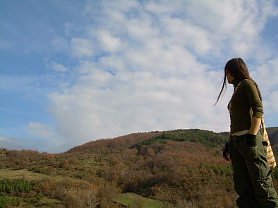standing woman looking over the right shoulder near mountains during day thumbnail