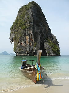 boat on shore in front rock formation thumbnail
