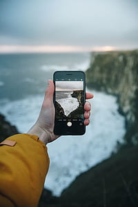 person holding smartphone taking photo of sea thumbnail