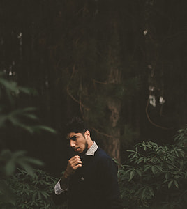 man standing near tree trunk thumbnail