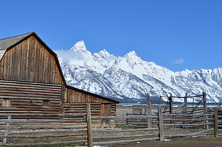 brown wooden house near snow covered mountain thumbnail