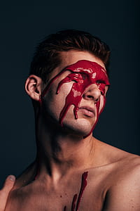 man with red paint on face covered his eyes photo thumbnail