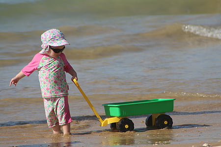 child pulling wagon on shore thumbnail