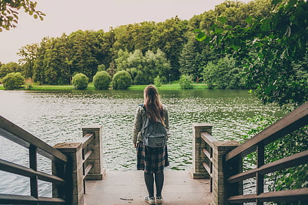 woman wearing gray backpack standing in front of green leafed trees during daytime thumbnail