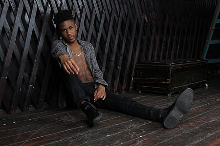 man sitting on black wooden floor thumbnail