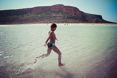 boy wearing brief running on seashore thumbnail