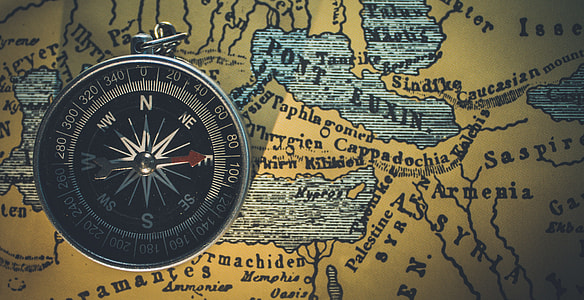 round silver-colored compass on top of brown map thumbnail
