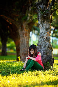woman in pink cold-shoulder shirt and green leggings sitting under tree thumbnail
