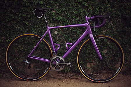 purple road bike leaning on green wall thumbnail