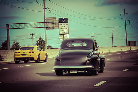vintage black vehicle traveling on road thumbnail