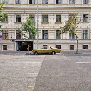 green coupe parked beside white building thumbnail