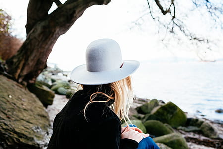 woman sitting on rock near body of water thumbnail