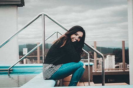woman wearing black sweater sitting near swimming pool thumbnail