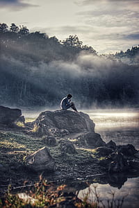 Man in Gray Shit Sitting on Rock Boulder thumbnail