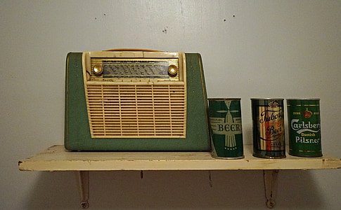 green and brown transistor radio beside three assorted cans thumbnail