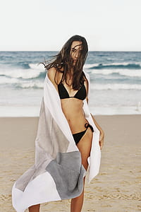 woman standing covering with mat beside seashore thumbnail