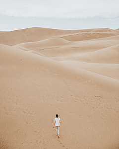 man in white shirt walking on desert thumbnail
