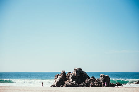 Tourists on a rocky seashore in sunlight with horizon in the background thumbnail