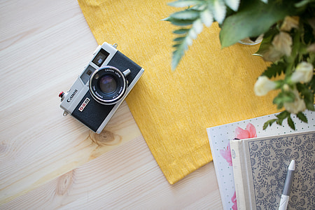 white and black Canon point-and-shoot camera on brown wooden surface thumbnail