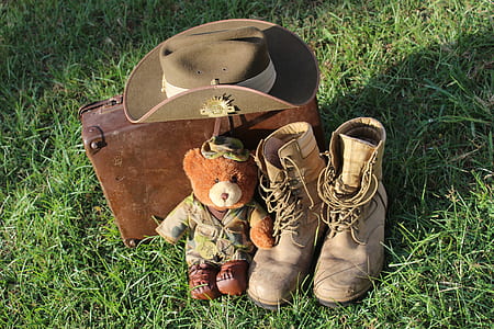 brown bear plush toy beside pair of combat boots thumbnail