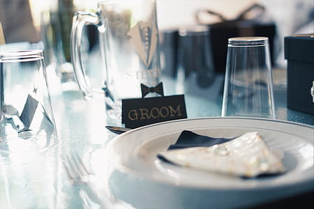 Round White Ceramic Plate Near Glass Cups and Groom Sign thumbnail