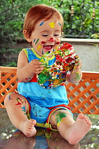 boy wearing blue shirt holding paint on table thumbnail