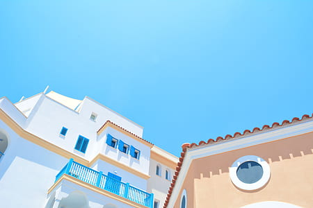 low angle photo of white and blue concrete house under blue clouds at daytime thumbnail