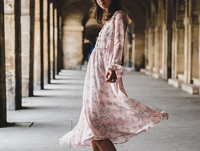 woman in pink and gray dress standing in between building thumbnail