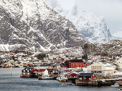 assorted-color concrete house near mountain covered by snow during daytime thumbnail
