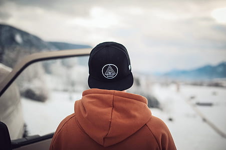 Person Wearing Black Cap and Orange Hoodie Turning His Back thumbnail