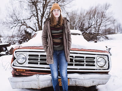 woman standing in front of vehicle covered with snow during daytime thumbnail