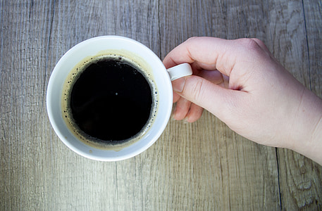 person holding white ceramic mug filled with black coffee thumbnail