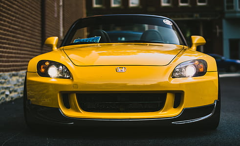 yellow Honda S2000 parked near brown concrete wall building thumbnail