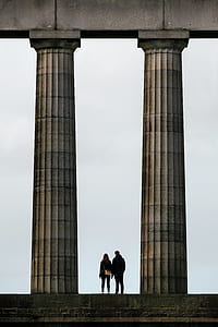 woman and man standing between concrete columns thumbnail