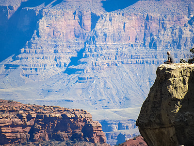aerial photography of man sitting on cliff thumbnail