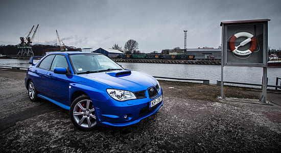 blue Subaru Impreza sedan parked near body of water at daytime thumbnail