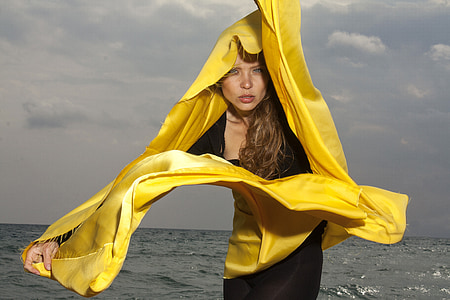 woman in black dress and yellow scarf near body of water at daytime thumbnail