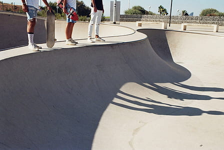 three persons beside gray concrete skateboard ramp thumbnail