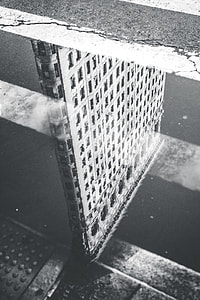 grayscale photo of concrete building reflecting on water thumbnail
