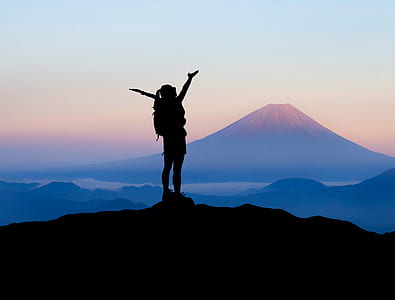 silhouette of woman raising her hands on top of mountain during daytime thumbnail