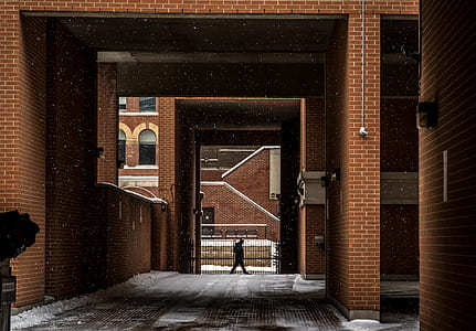 man walking under brown building thumbnail