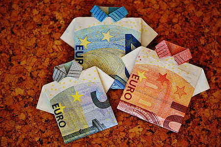 close-up photo of three folded Euro banknotes on brown surface thumbnail