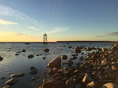 brown tower near shoreline filled with rocks thumbnail