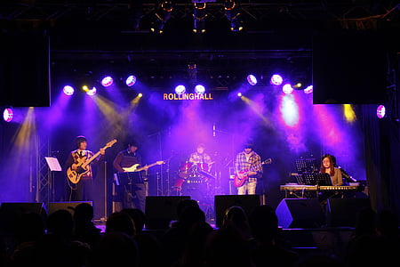 group of band playing on the stage with purple lights thumbnail