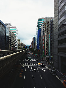 vehicle on the road near high-rise buildings under white sky thumbnail