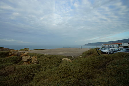 Parked Vehicle Near Body of Water Under Cloudy Sky thumbnail