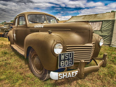 classic brown vehicle near green and white tent at daytime thumbnail