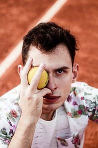man covering his right eyes with a tennis ball thumbnail
