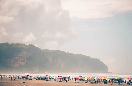 group of people on beach sand near umbrella thumbnail