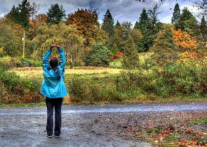 woman stretching arms standing near body of water thumbnail